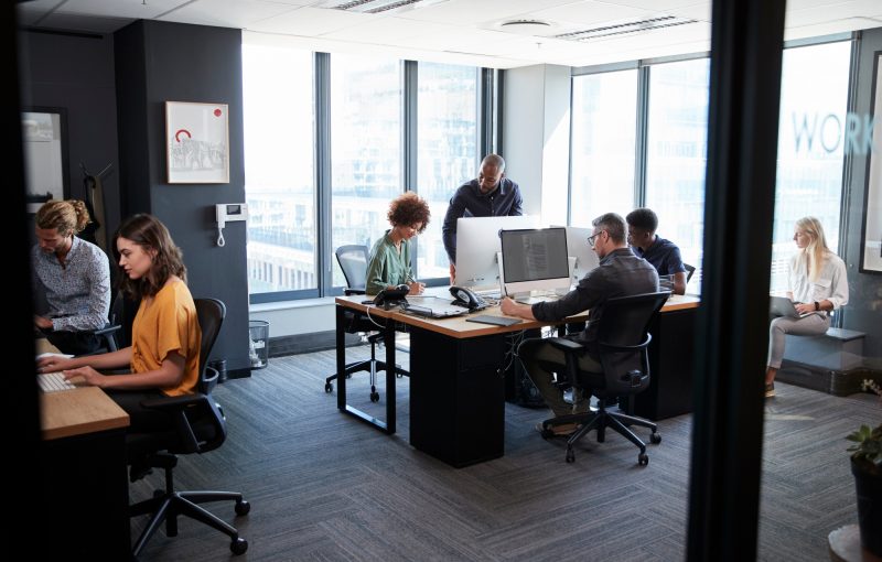 Young creative team working together at computers in a casual office, seen from doorway
